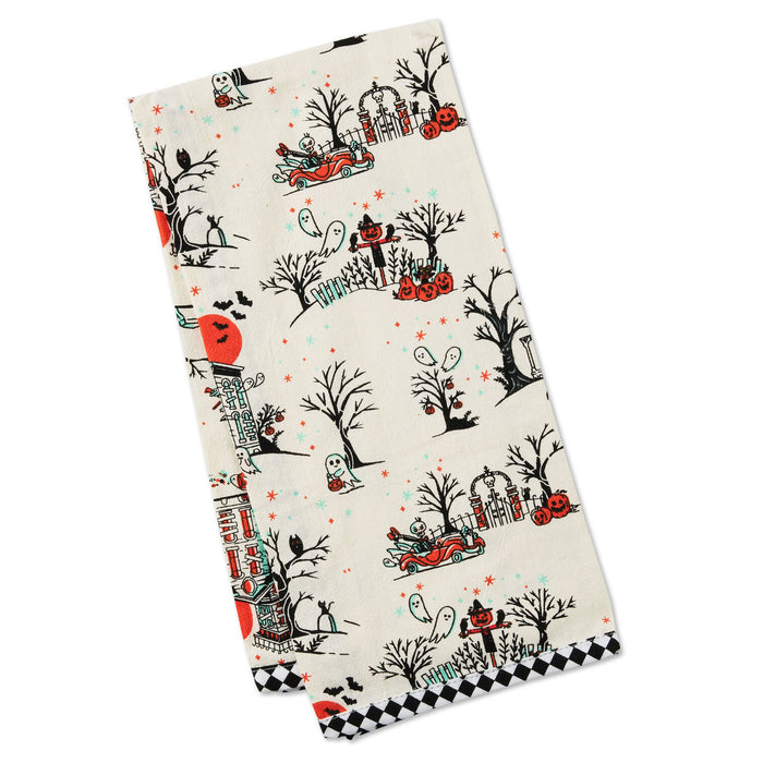 A rectangular kitchen towel with a Halloween-themed pattern featuring pumpkins, ghosts, haunted houses, and trees on an off-white background, finished with a black and white checkered border.