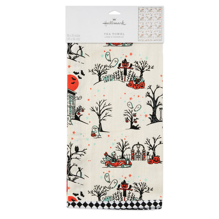 A packaged Hallmark tea towel featuring a Halloween-themed pattern with black trees, orange pumpkins, a ghost, a witch riding a red sleigh, and small red stars on an off-white background.