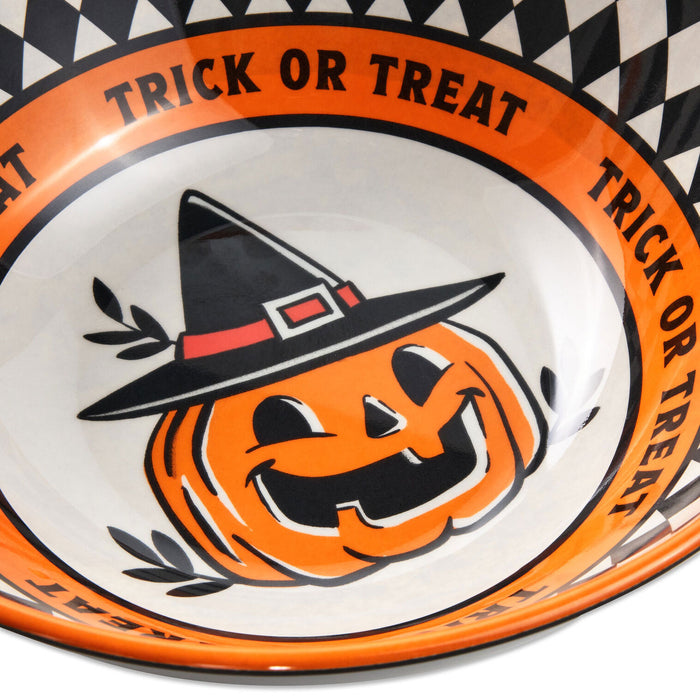 A close-up of a Halloween-themed bowl with an orange rim printed with the words 'TRICK OR TREAT' and a black-and-white check border. The center shows a smiling orange jack-o'-lantern wearing a black witch hat with a red band.