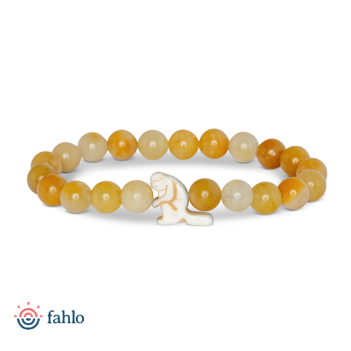 A beaded stretch bracelet featuring round translucent yellow and orange beads with a small white ceramic beaver charm in the center, displayed on a clean white background with the 'fahlo' brand logo in the bottom-left corner.