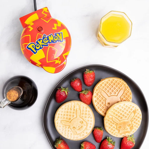 Pokémon-themed waffle maker with waffles and strawberries on a white background