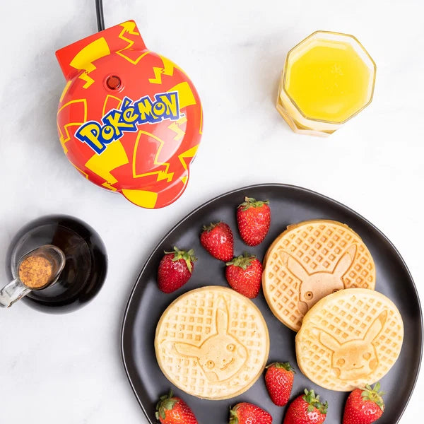 Pokémon-themed waffle maker with waffles and strawberries on a white background