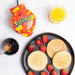 Pokémon-themed waffle maker with waffles and strawberries on a white background