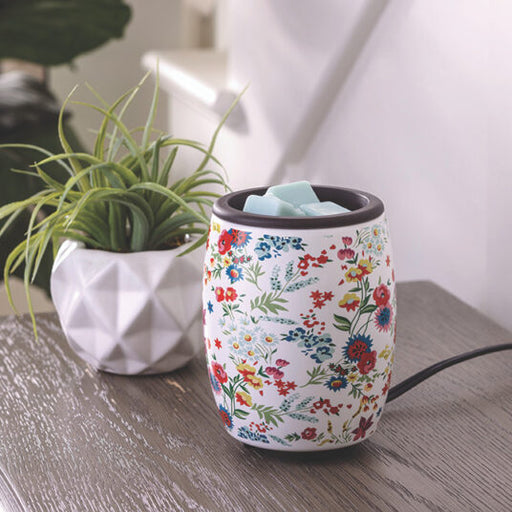 Floral-patterned diffuser on a wooden surface with a plant in the background