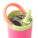 Pink and green tumbler with an orange handle and straw on a white background