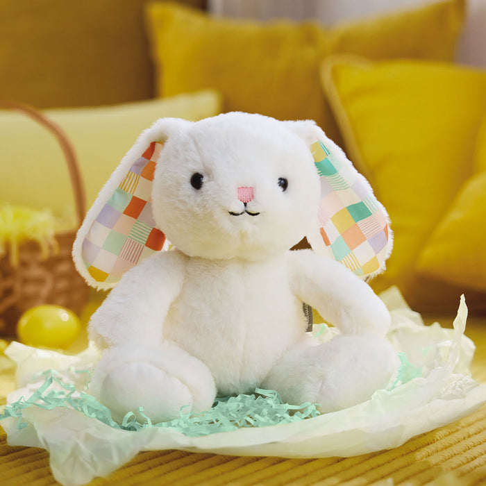 White plush bunny with colorful ears on a yellow couch
