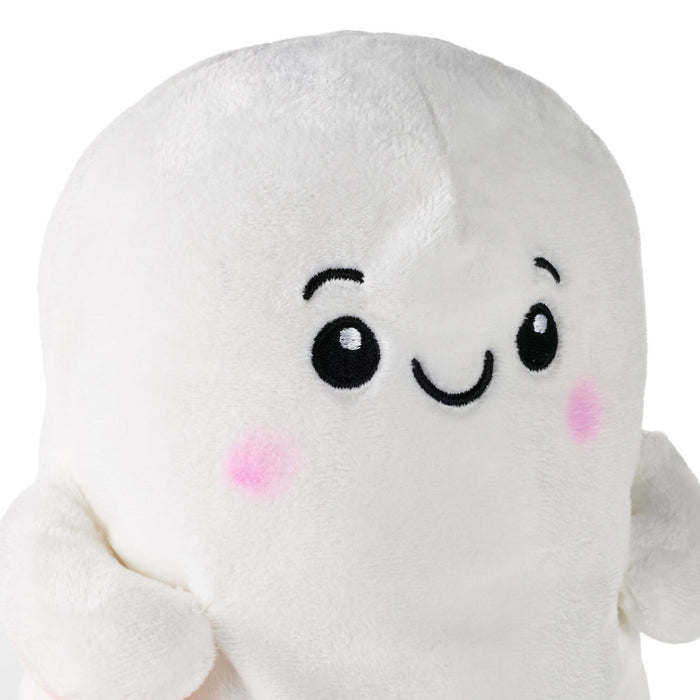 A close-up of a white plush toy with a cute cartoon face, featuring black embroidered eyes and a smiling mouth, with pink embroidered cheeks.