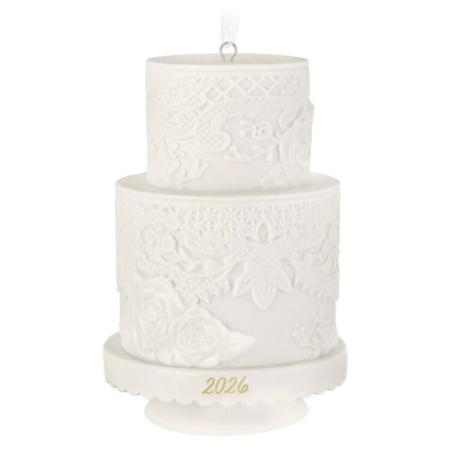 Two-tiered white cake ornament with intricate patterns and '2026' on a white background