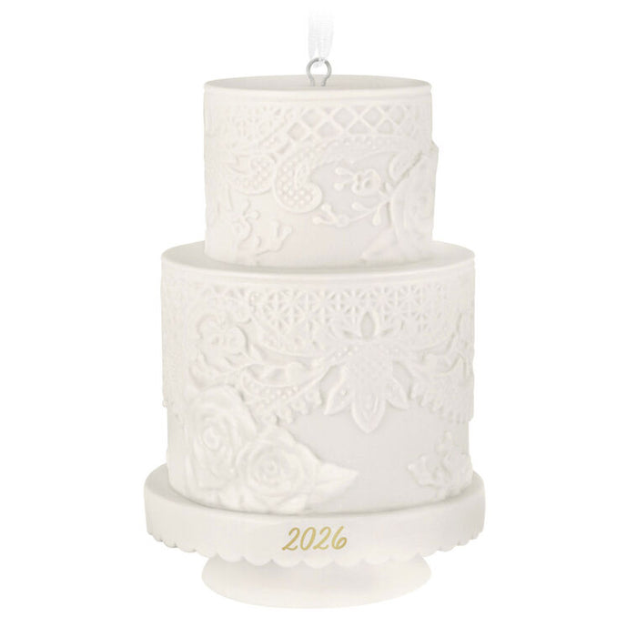 Two-tiered white cake ornament with intricate patterns and '2026' on a white background