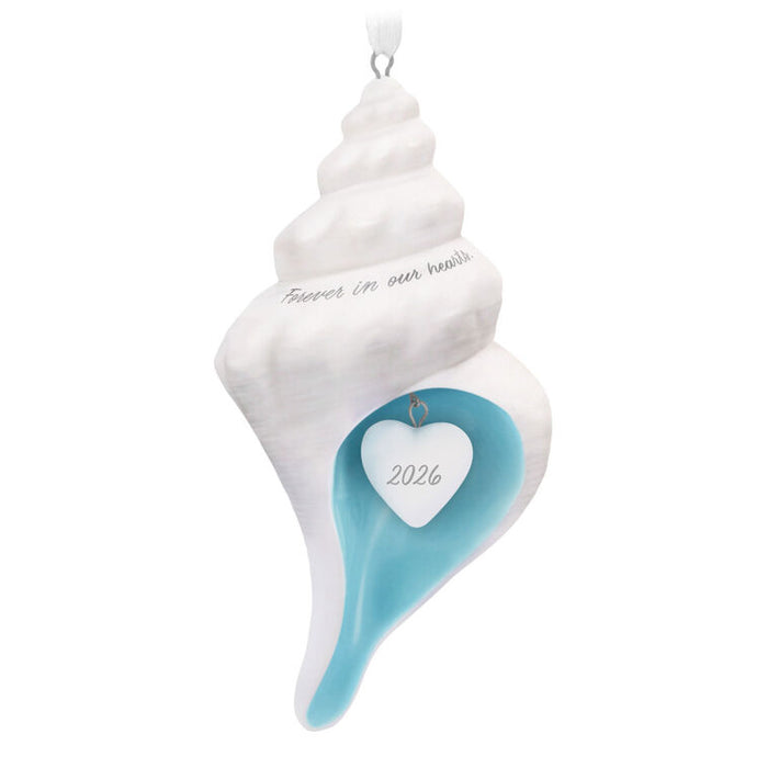 Decorative shell ornament with 'Forever in our hearts' and '2026' on a white background