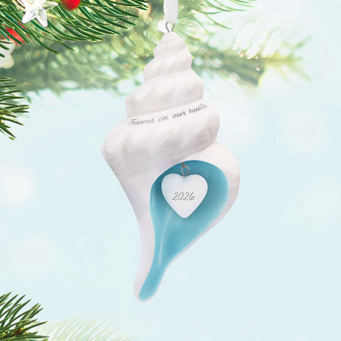 Decorative shell ornament with 'Friends in our hearts' and '2026' on a Christmas tree background