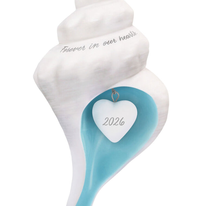 Decorative shell with a heart-shaped tag displaying '2026' on a white background