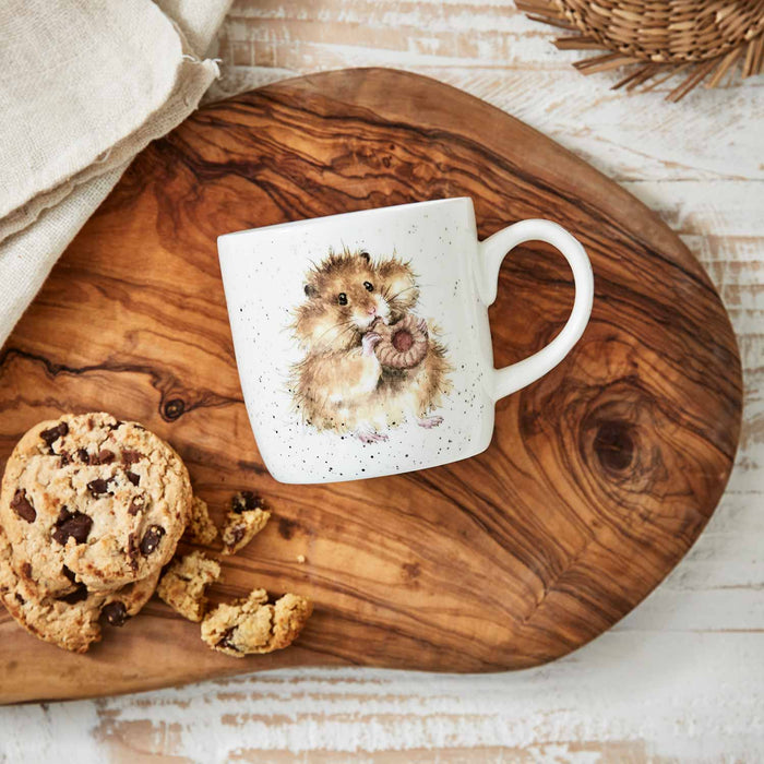White mug with a hamster design on a wooden board with cookies