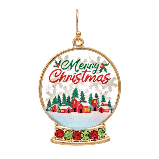 A gold-toned Christmas snow globe earring featuring a festive winter village scene with red cabins, evergreen trees, and 'Merry Christmas' lettering in green and red on a white background.
