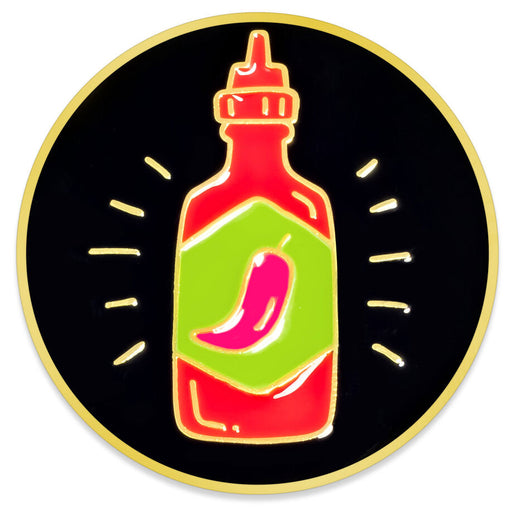 A circular enamel pin featuring a stylized red chili sauce bottle with a green label and pink chili pepper, set against a black background with small white light rays and a gold border.