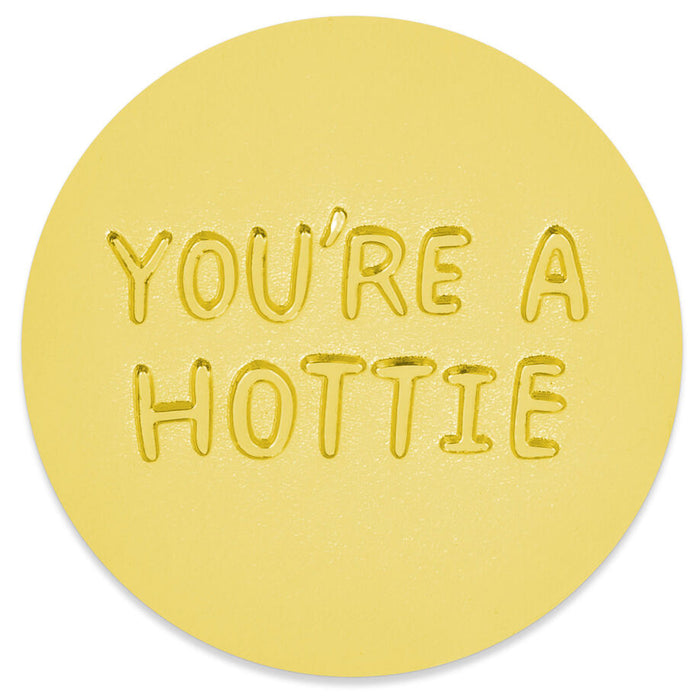 A round yellow coaster with the phrase 'YOU'RE A HOTTIE' embossed in raised letters, shown on a clean white background.