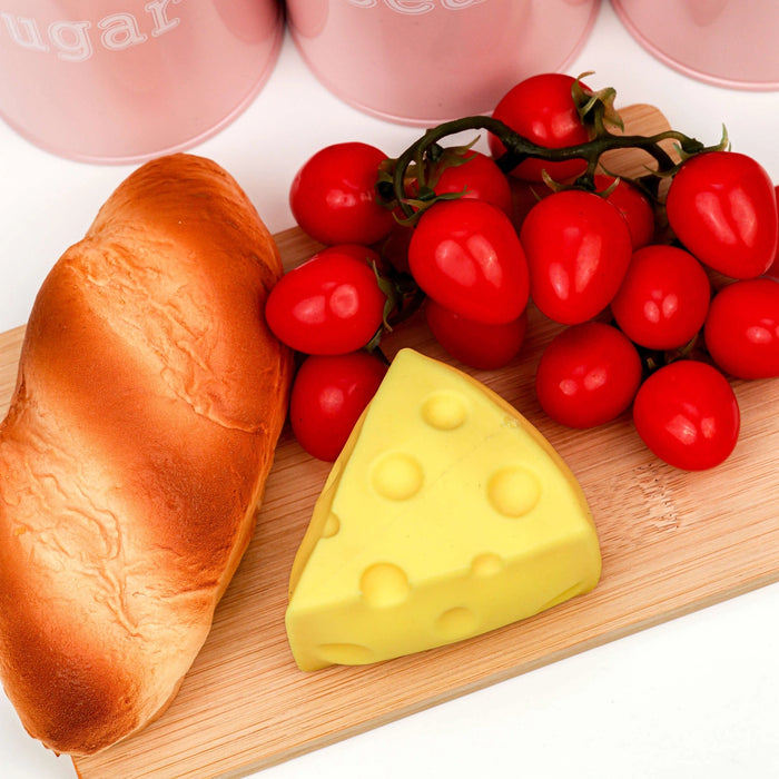 Bread, cheese, and cherry tomatoes on a wooden board with a white background