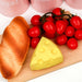 Bread, cheese, and cherry tomatoes on a wooden board with a white background