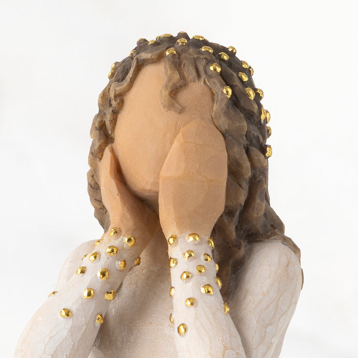 Wooden figurine with braided hair and gold beads on a white background