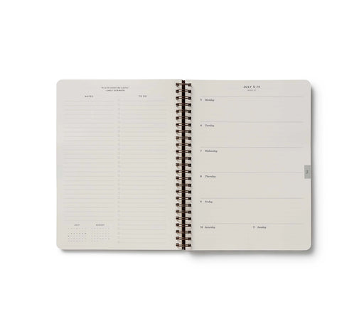 Open spiral-bound planner with grid and blank pages on a white background