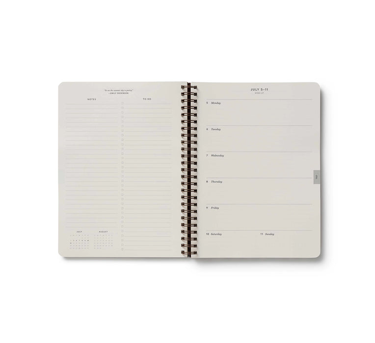 Open spiral-bound planner with grid and blank pages on a white background