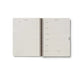 Open spiral-bound planner with grid and blank pages on a white background