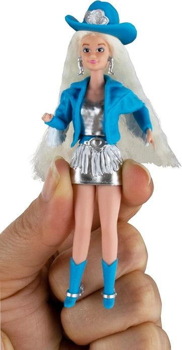 Toy doll with blue outfit and hat held by a hand on a white background