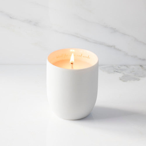 White candle in a ceramic holder with a marble background