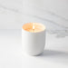White candle in a ceramic holder with a marble background