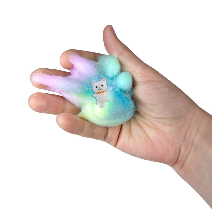 Hand holding a colorful paw-shaped squishy toy with a cat design on a white background