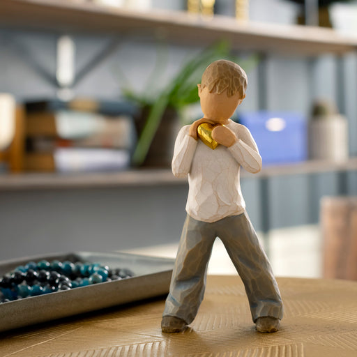Figurine of a child holding a gold heart in a blurred indoor setting
