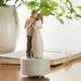Statue of a couple embracing on a wooden base with a blurred indoor background