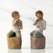 Two figurines of children holding 'I love you' signs on a white background