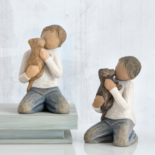 Two figurines of children holding teddy bears on a white background