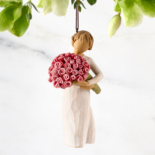 Decorative figurine of a woman holding pink flowers against a white background