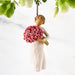 Decorative figurine of a woman holding pink flowers against a white background
