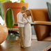 Statue of a couple embracing on a wooden table with a blurred indoor background