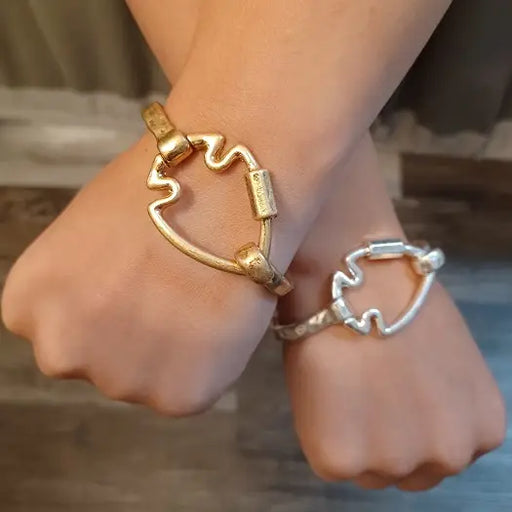 Close-up of hands wearing gold and silver bracelets on a blurred background