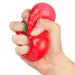 A hand squeezing a red, pepper-shaped stress toy with a small green stem detail, isolated on a white background.