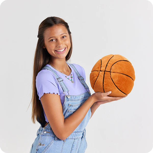 Young girl holding a plush basketball against a plain background