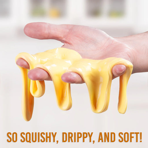 Hand holding yellow gooey substance with text 'So squishy, drippy, and soft!' on a blurred background