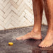 Person standing on a wet floor with a shower head in the background