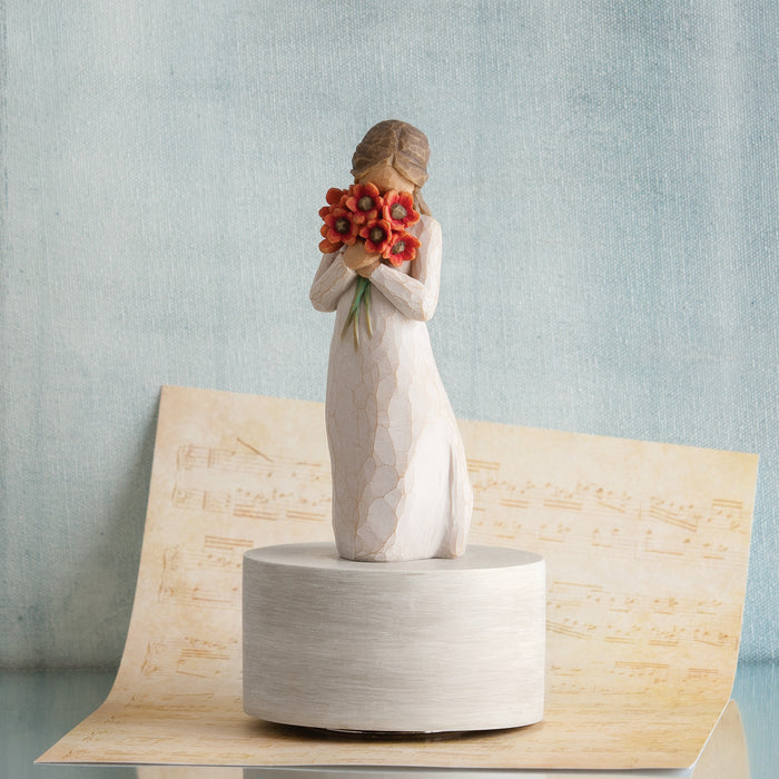 Decorative figurine of a woman holding flowers on a textured surface with a light blue background