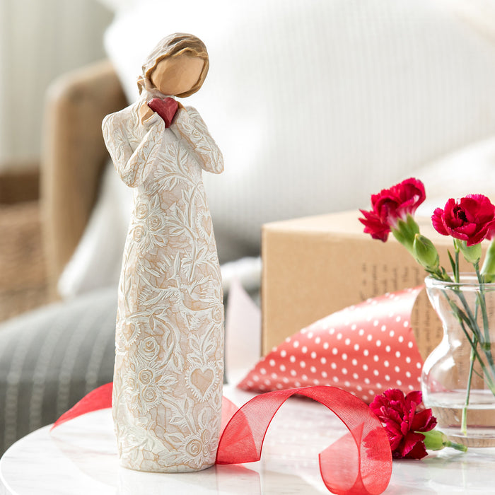 Decorative figurine with red ribbon and flowers on a surface