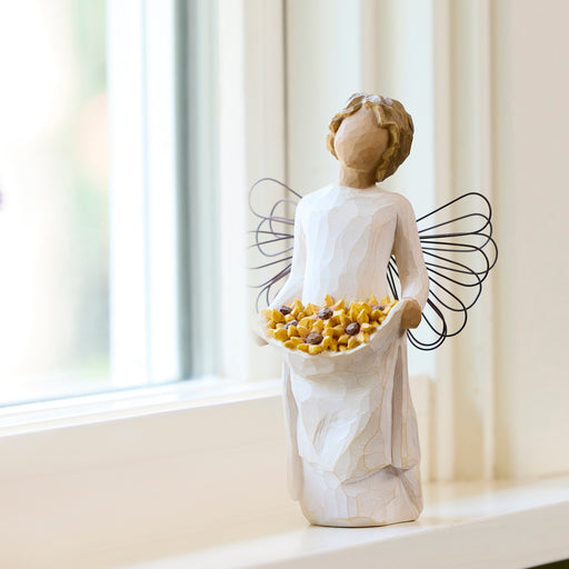 Standing angel with darker skin tone and hair color, in cream dress and wire wings, holding up skirt filled with black-eyed susan flowers