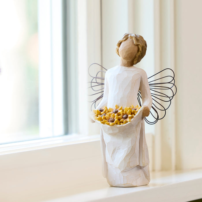Standing angel with darker skin tone and hair color, in cream dress and wire wings, holding up skirt filled with black-eyed susan flowers