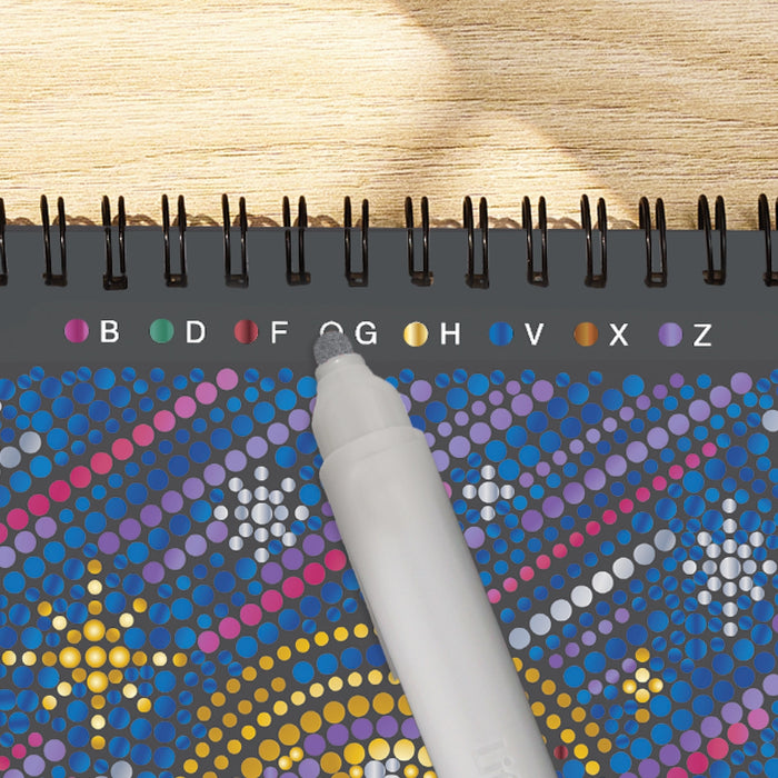 Colorful dot-to-dot book with a hand holding a pen on a wooden surface