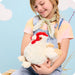 Young girl holding a plush rooster toy against a light blue background