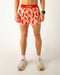 Person wearing a red waistband and shorts with chili pepper pattern on a plain background