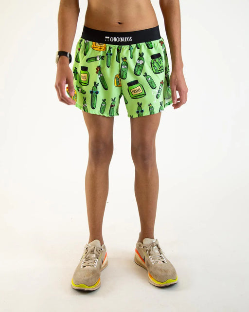Person wearing green shorts with a pattern of bottles on a white background